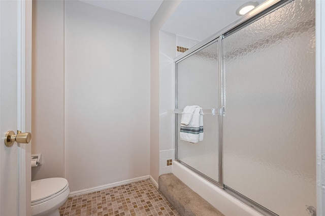 bathroom featuring baseboards, toilet, and a shower stall