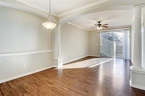 unfurnished room with baseboards, decorative columns, and wood finished floors