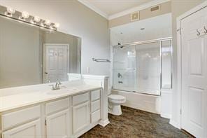 bathroom with vanity, ornamental molding, combined bath / shower with glass door, and toilet
