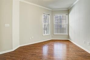 spare room featuring crown molding, baseboards, and wood finished floors