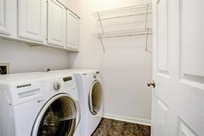 laundry room with independent washer and dryer, baseboards, and cabinet space