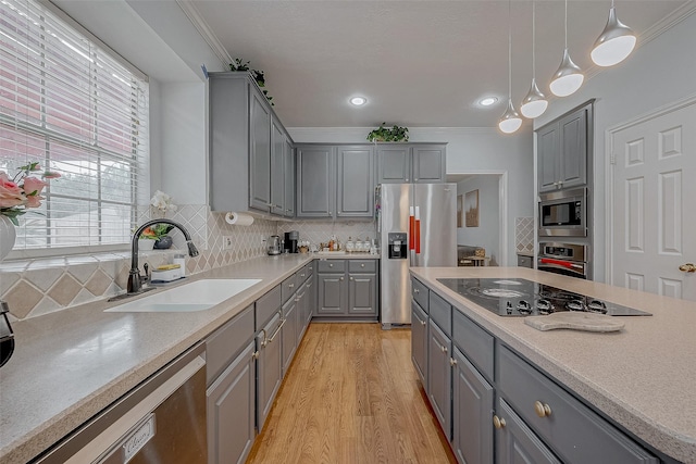 kitchen featuring gray cabinetry, appliances with stainless steel finishes, a sink, light wood-type flooring, and light countertops