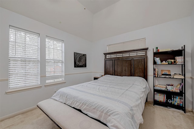 bedroom featuring light colored carpet, baseboards, and lofted ceiling