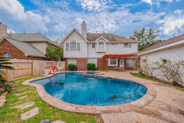 view of swimming pool with a patio, fence, and a pool with connected hot tub