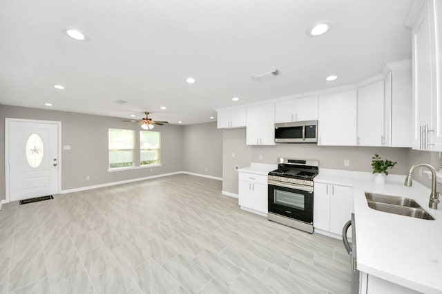 kitchen with white cabinets, ceiling fan, a sink, light countertops, and stainless steel appliances