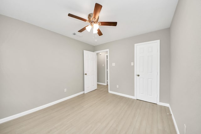 unfurnished bedroom featuring a ceiling fan, baseboards, visible vents, and light wood-style flooring