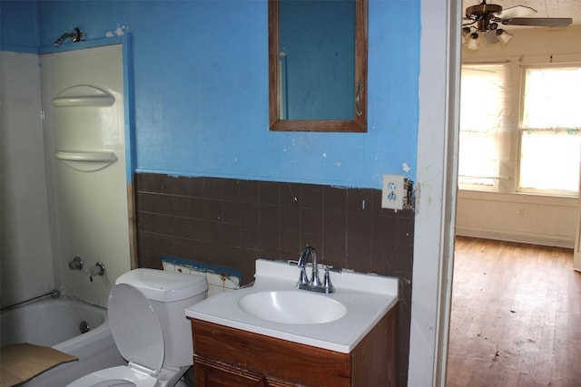 bathroom with ceiling fan, wood finished floors, vanity, toilet, and tub / shower combination