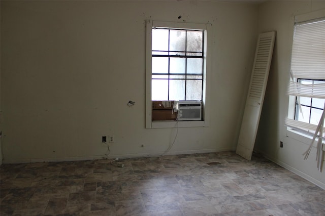 spare room with stone finish floor, plenty of natural light, and baseboards