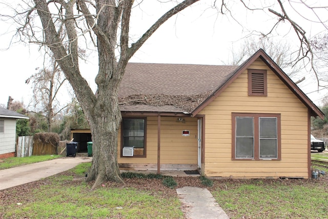 bungalow-style home with roof with shingles and fence