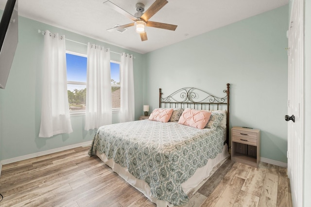 bedroom featuring a ceiling fan, baseboards, and light wood finished floors