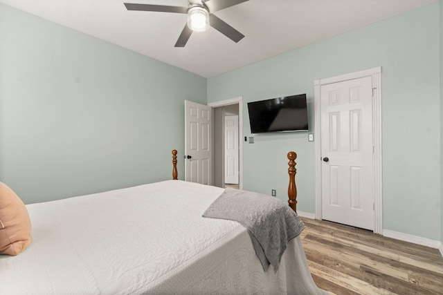 bedroom with baseboards, a ceiling fan, and light wood-style flooring