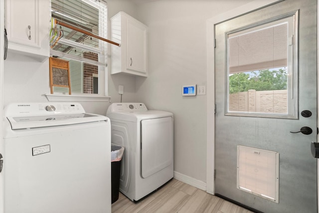 laundry area featuring cabinet space, baseboards, washing machine and dryer, and light wood-style floors