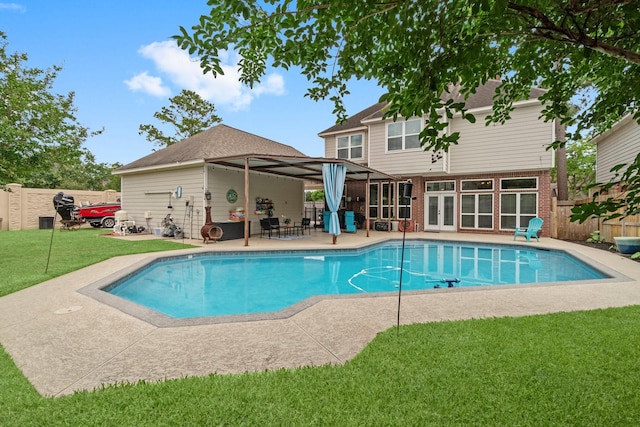 view of swimming pool with french doors, a lawn, a fenced in pool, a fenced backyard, and a patio