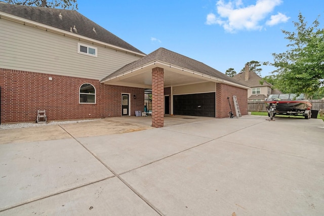 rear view of property with fence, an attached carport, concrete driveway, and brick siding