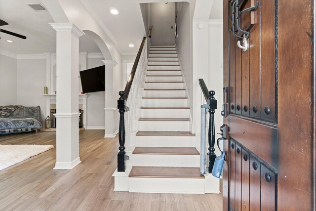 stairway featuring crown molding, a ceiling fan, wood finished floors, and visible vents