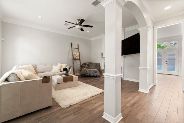 living area with ceiling fan, visible vents, arched walkways, wood finished floors, and ornate columns