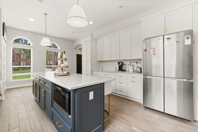 kitchen with freestanding refrigerator, white cabinetry, and built in microwave