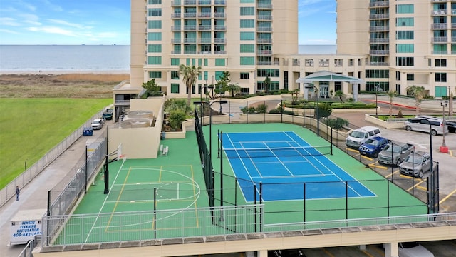view of tennis court featuring a water view and fence