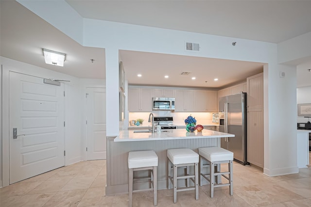 kitchen featuring a kitchen bar, visible vents, appliances with stainless steel finishes, a sink, and light countertops