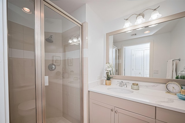 full bath featuring vanity, a stall shower, toilet, and visible vents
