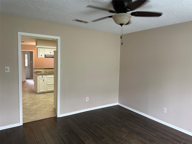 unfurnished room featuring a ceiling fan, a textured ceiling, visible vents, wood finished floors, and baseboards