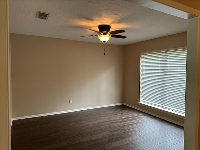 empty room featuring baseboards, a textured ceiling, dark wood-style floors, and ceiling fan