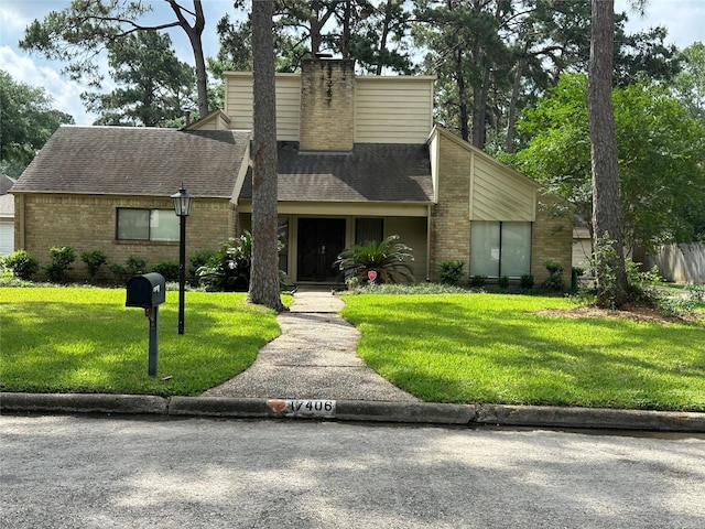 view of front of house with brick siding, roof with shingles, a chimney, and a front yard