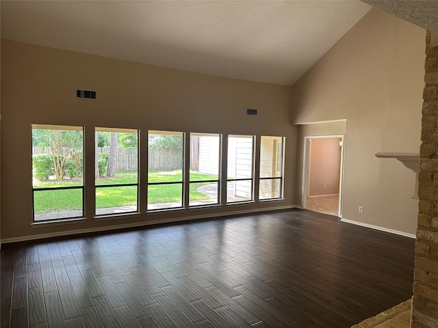 unfurnished living room with high vaulted ceiling, dark wood finished floors, and visible vents