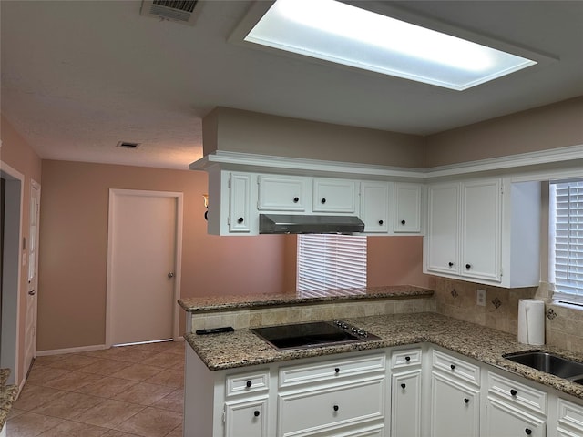 kitchen with black electric cooktop, under cabinet range hood, and white cabinets