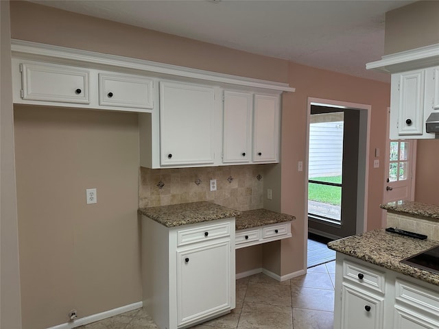 kitchen featuring white cabinets, baseboards, stone countertops, and decorative backsplash