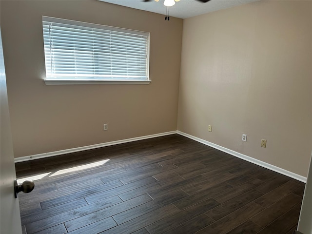 empty room featuring baseboards, a ceiling fan, and dark wood-style flooring