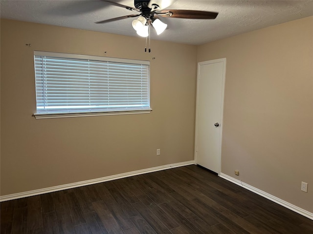 unfurnished room featuring dark wood-style flooring, a ceiling fan, and baseboards