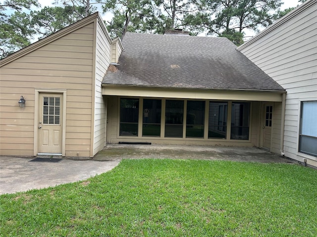 rear view of property with a lawn, a shingled roof, and a patio area