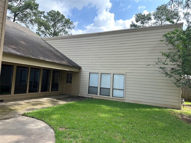 rear view of property with roof with shingles, a patio, and a yard