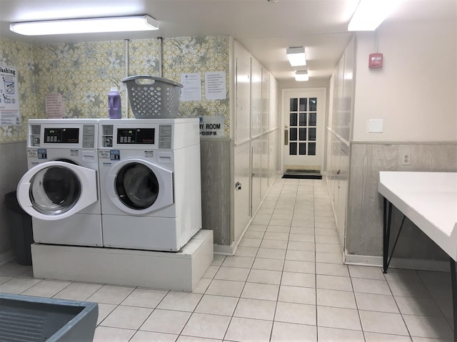 community laundry room with wainscoting, independent washer and dryer, light tile patterned flooring, and tile walls