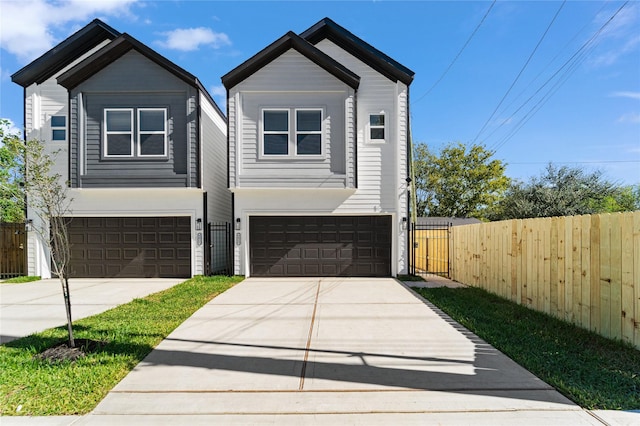 contemporary house with concrete driveway, an attached garage, fence, and a gate