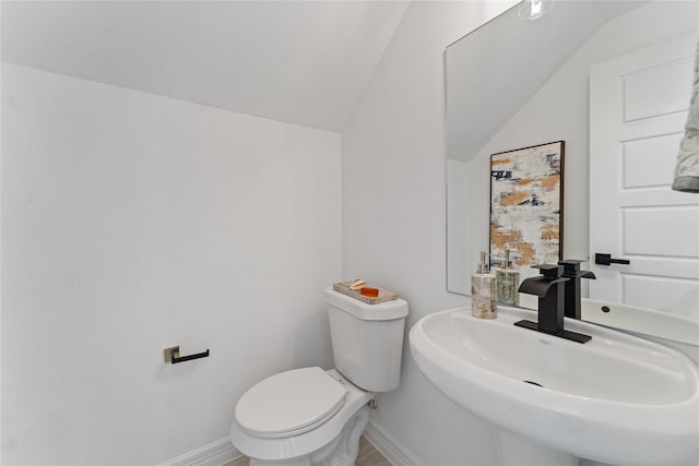 half bathroom with a sink, baseboards, vaulted ceiling, and toilet