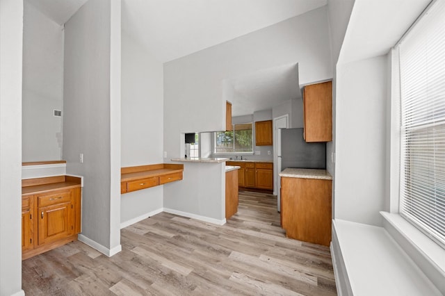 8803 Enchanted Forest Dr, Houston, TX 77088 - kitchen featuring brown cabinetry, a peninsula, high vaulted ceiling, light wood-type flooring, and light countertops