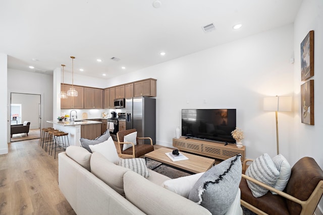 living area with recessed lighting, baseboards, visible vents, and light wood-type flooring