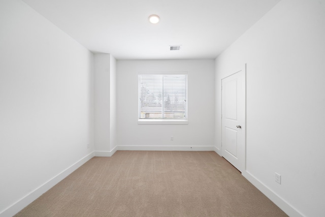 unfurnished room with visible vents, baseboards, and light colored carpet