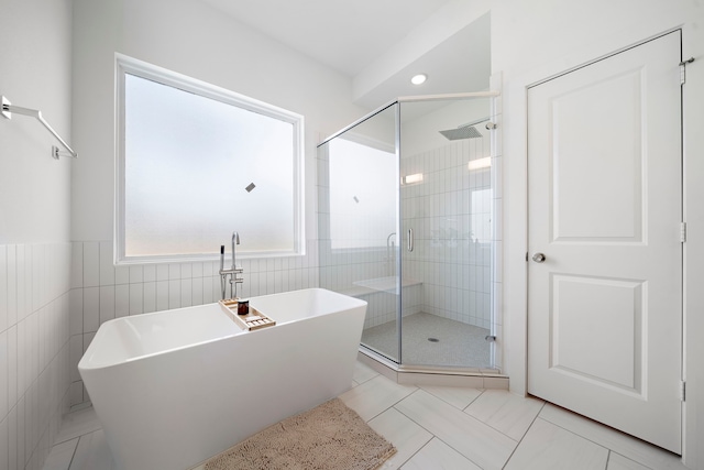 full bath featuring a soaking tub, tile walls, and a shower stall