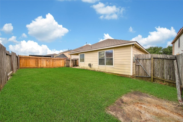 back of property with a fenced backyard, a yard, and a shingled roof