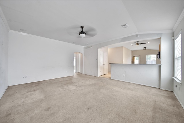 unfurnished living room with arched walkways, ornamental molding, a ceiling fan, and carpet flooring