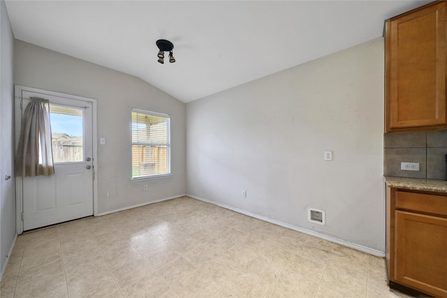 unfurnished dining area with baseboards and vaulted ceiling