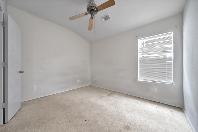 carpeted empty room with ceiling fan, visible vents, baseboards, and lofted ceiling