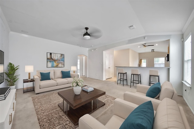 living area featuring ceiling fan, visible vents, crown molding, arched walkways, and baseboards
