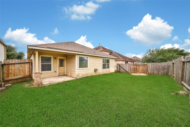 rear view of property featuring a lawn, roof with shingles, a fenced backyard, and a patio area