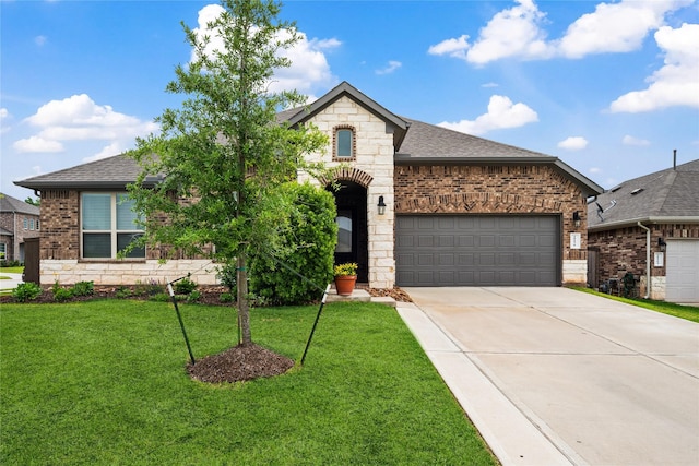 french country style house with a garage, a front yard, brick siding, a shingled roof, and driveway