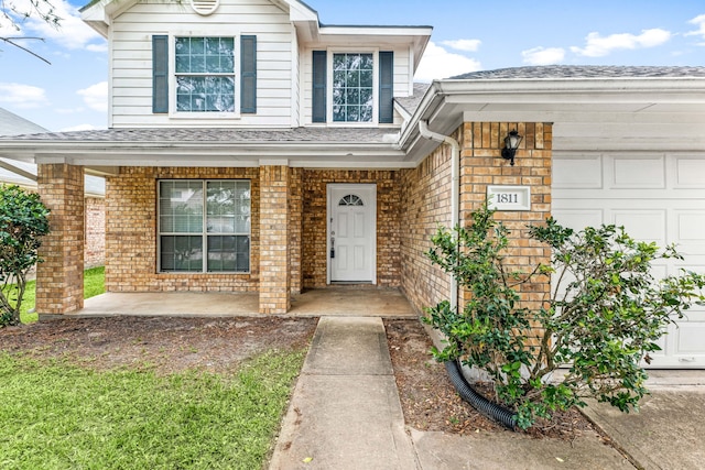 1811 Salt Valley Dr, Katy, TX 77493 - view of exterior entry with roof with shingles, an attached garage, a porch, and brick siding