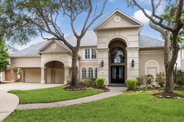 view of front of property featuring a front yard, driveway, french doors, and roof with shingles